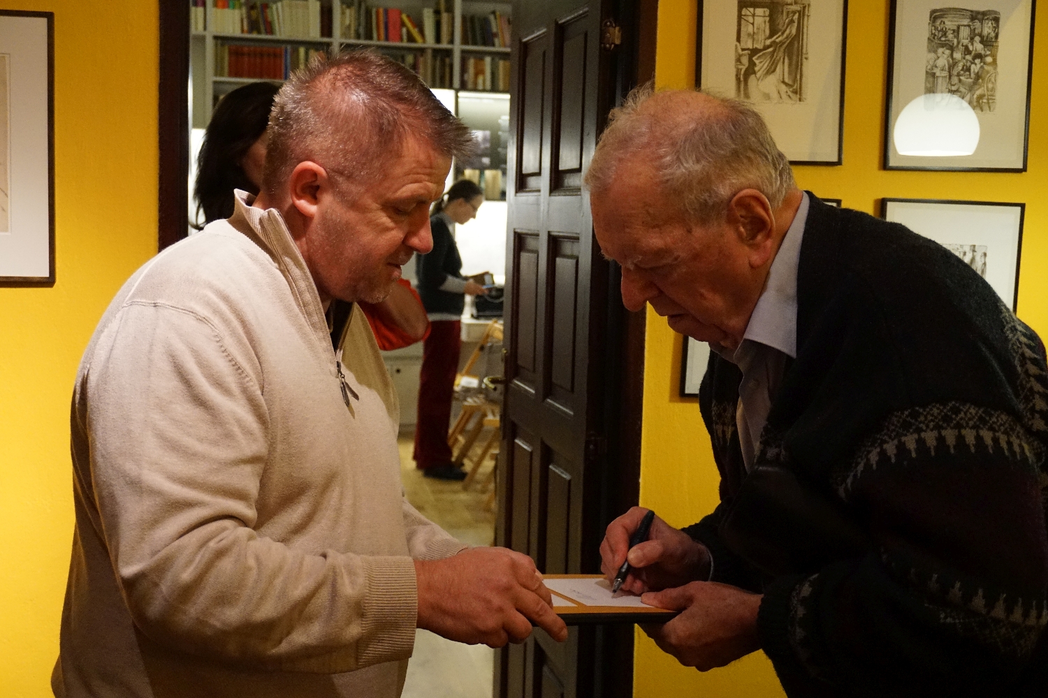 Milan Uhde (rechts) signiert sein Buch. Foto: Konstantin Kountouroyanis